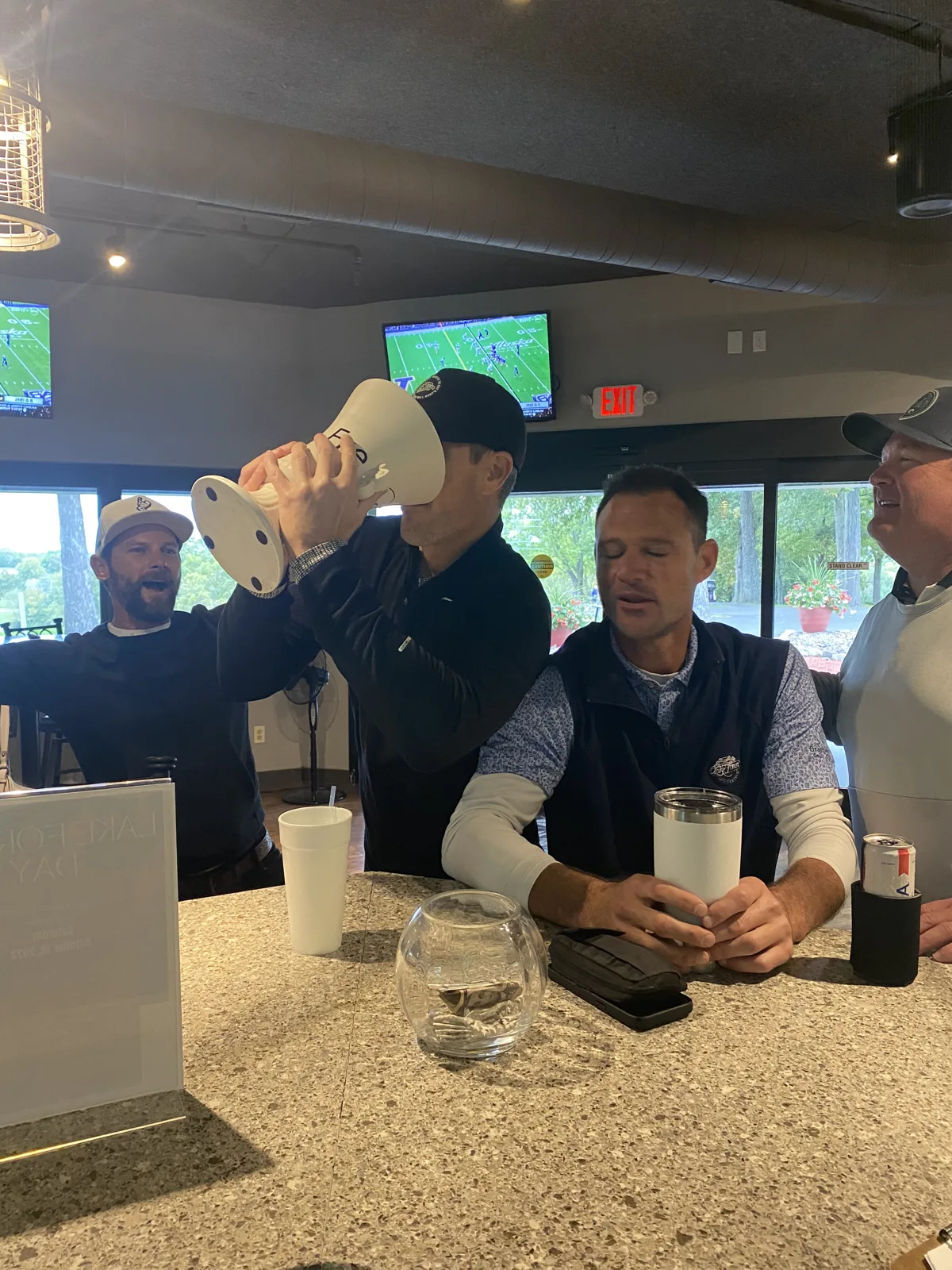 Friends gathered around a clubhouse table with the trophy